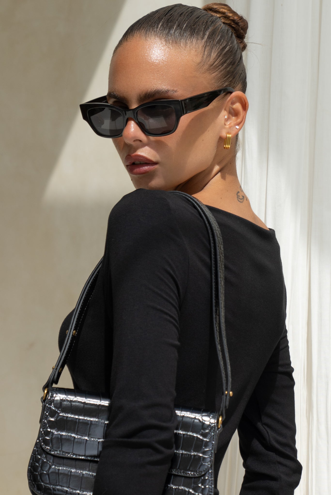 close up of woman wearing black maxi dress, sunglasses and black leather bag