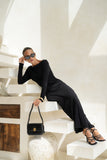 woman wearing a black long sleeve maxi dress leaning on stairs holding a black leather shoulder bag woman wearing a black long sleeve maxi dress leaning on stairs holding a black leather shoulder bag