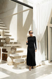 woman wearing a black long sleeve maxi dress, black shoulder bag, sunglasses in front of some stairs woman wearing a black long sleeve maxi dress, black shoulder bag, sunglasses in front of some stairs