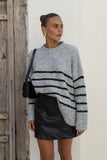 woman wearing grey black stripe sweater, black mini dress woman wearing grey black stripe sweater, black mini dress