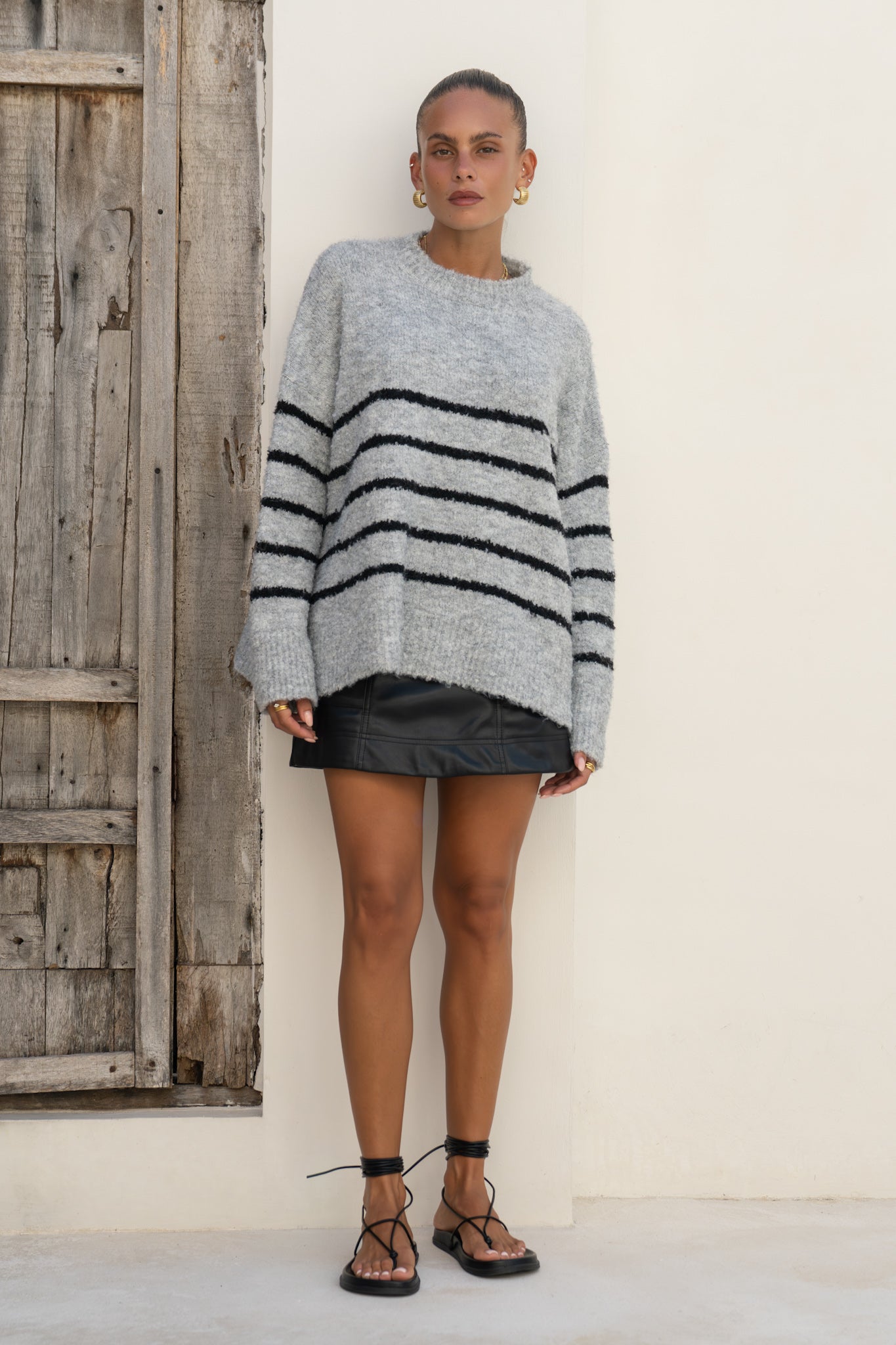 woman wearing grey black stripe knit sweater untucked