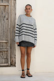 woman wearing grey black stripe knit sweater untucked woman wearing grey black stripe knit sweater untucked