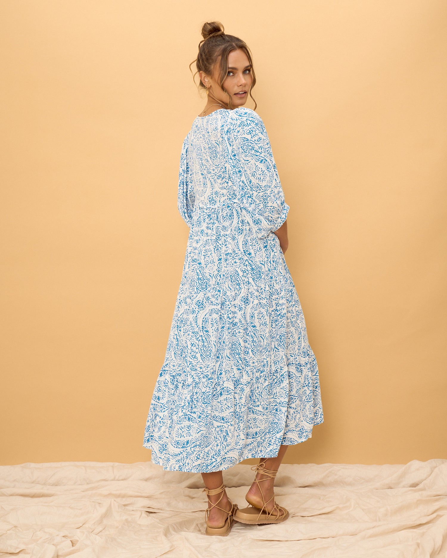 woman wearing a blue boho dress in front of a yellow background
