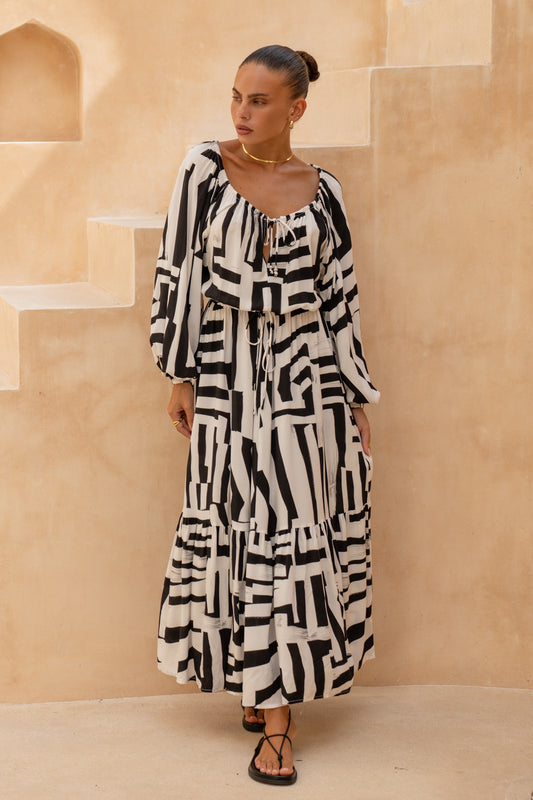 woman posing while wearing a black geometric long sleeve maxi dress