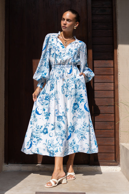 woman wearing a blue floral dress in front of a wooden door