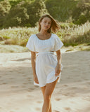 Woman wearing the etta white puffed sleeve mini dress with back cut out at the beach