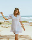 Woman wearing everleigh white puff sleeves mini dress at the beach