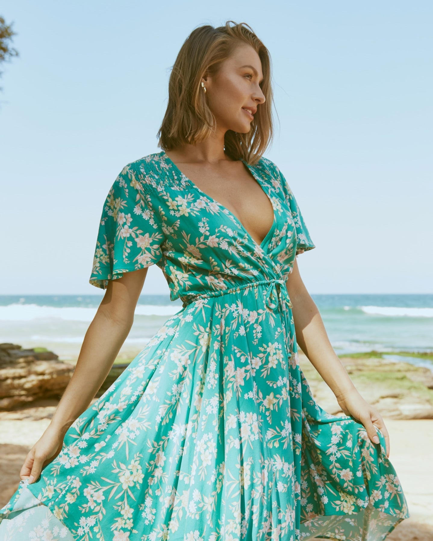 Woman wearing the raelynn v neck wrap high low dress at the beach
