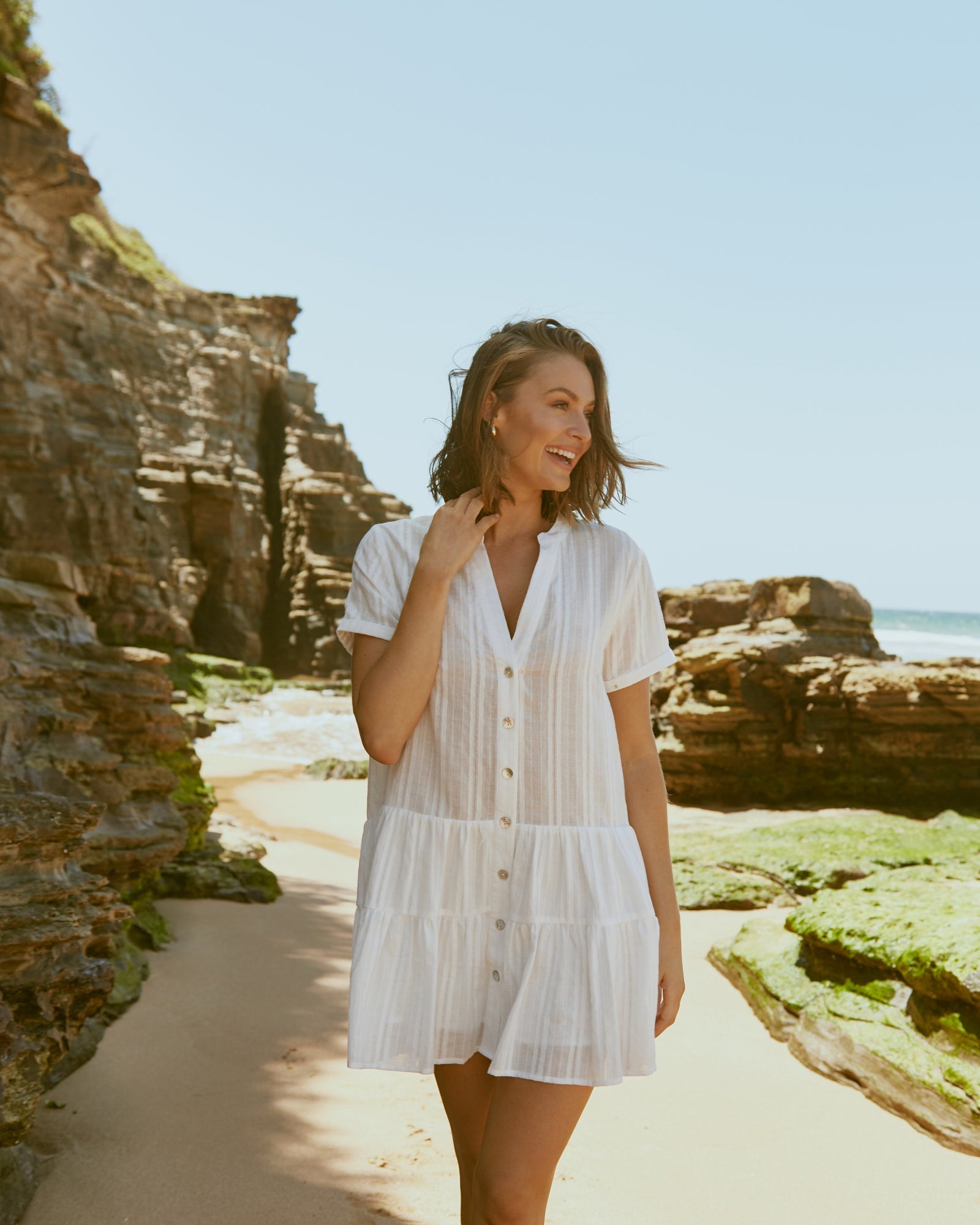 Woman wearing the valeria white button down mini dress at the beach