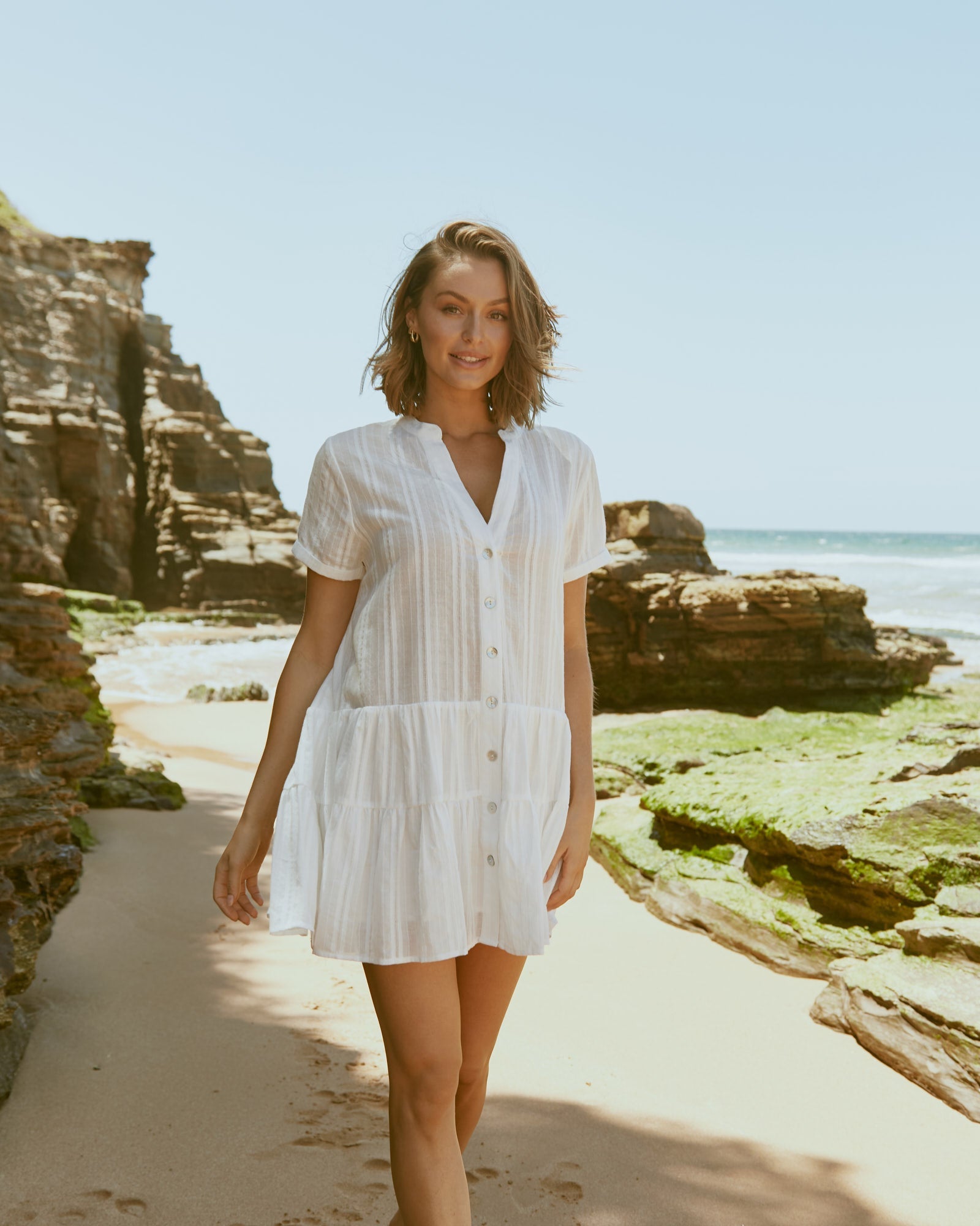 Woman wearing the valeria white button down mini dress at the beach